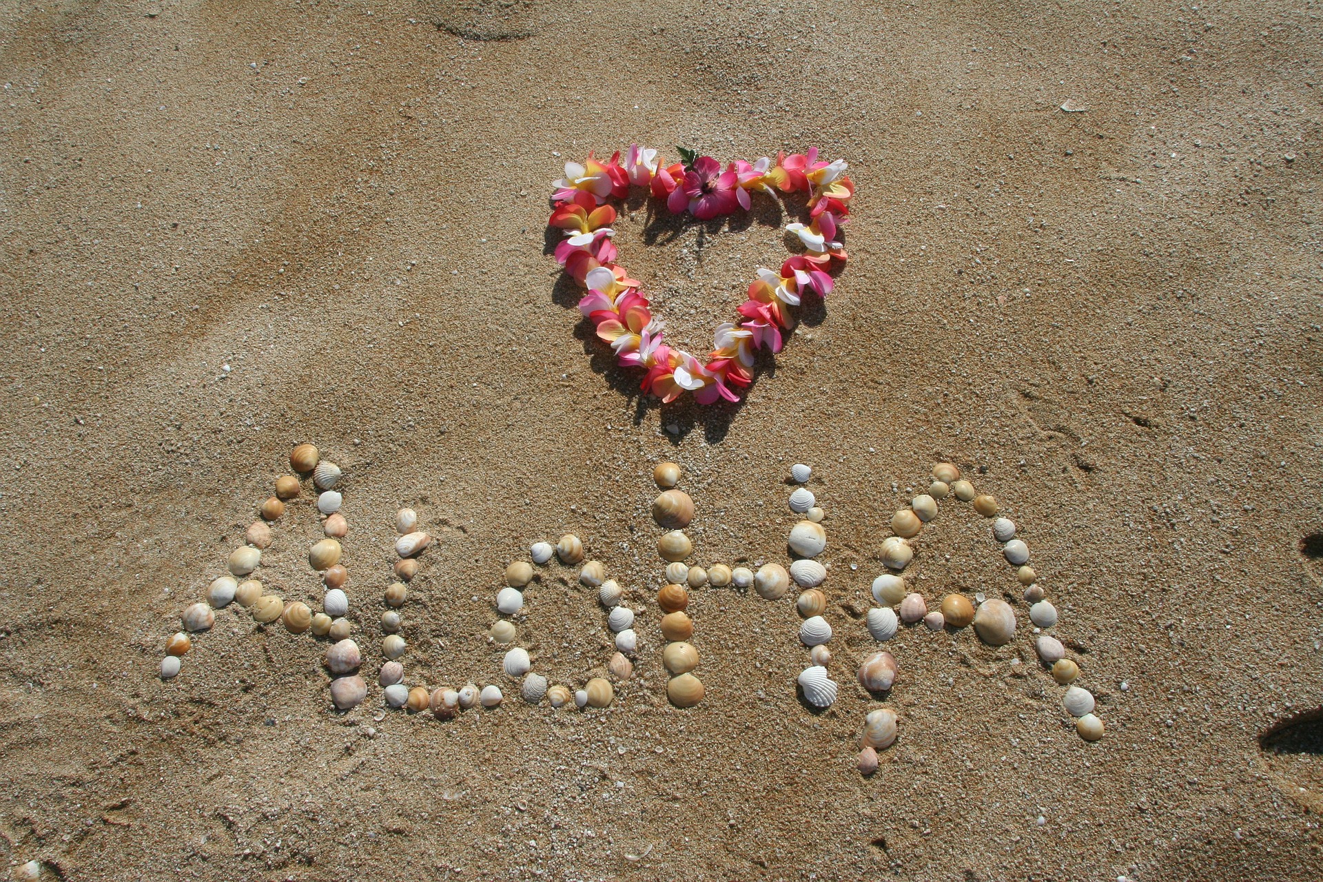 Foto am Strand mit Aloha-Schriftzug und Blumenkranz in Herzform