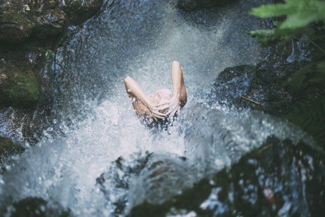 Foto einer duschenden Frau unter einem Wasserfall