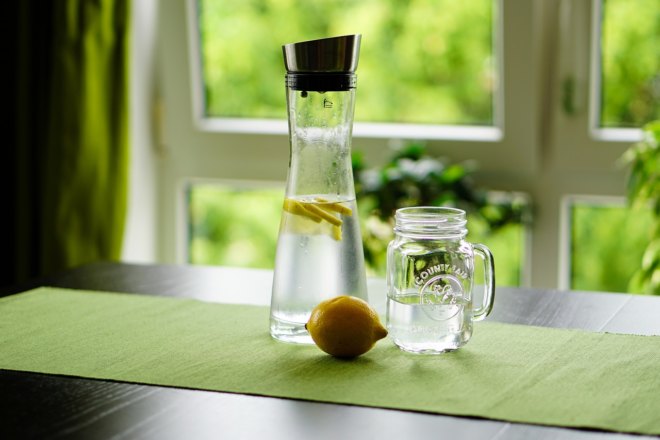 Foto einer Karaffe mit Wasser und Glas neben einer Zitrone